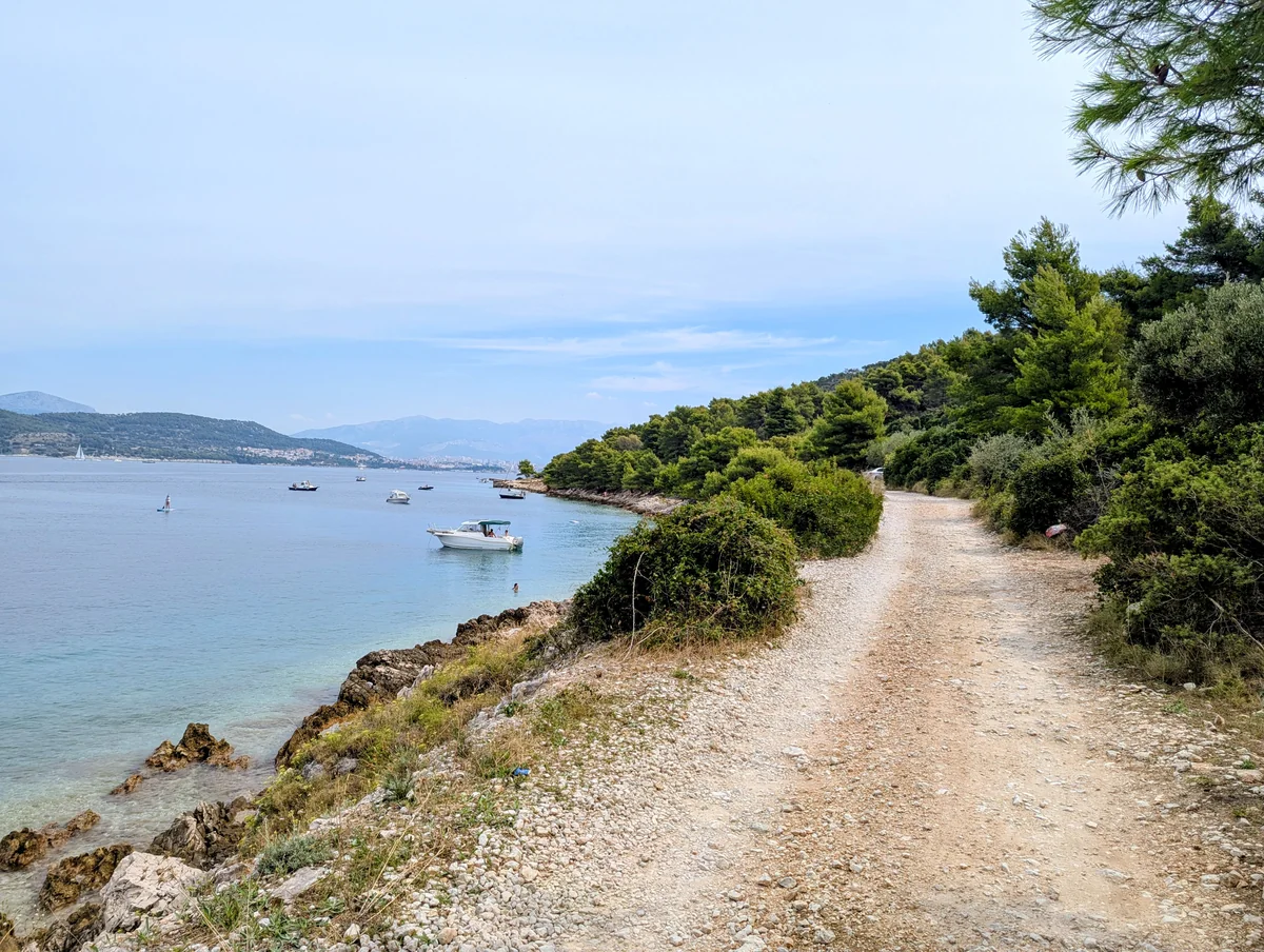 A gravel coastal trail on Čiovo with the sea and moored boats below