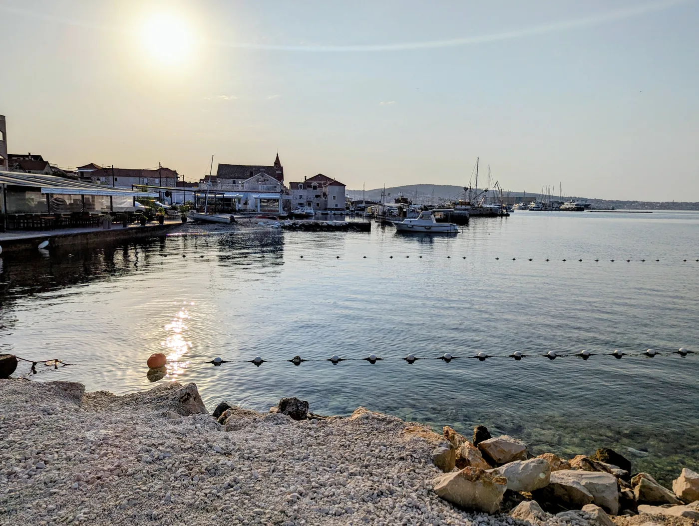 Low sun over the calm bay at Seget Donji, with the village church and moored boats along the shore