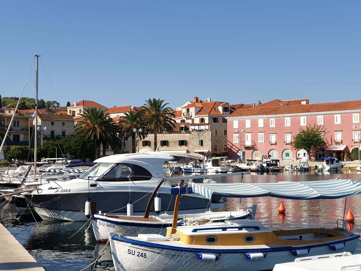 Small boats moored in Supetar harbour on Brač with palm trees behind