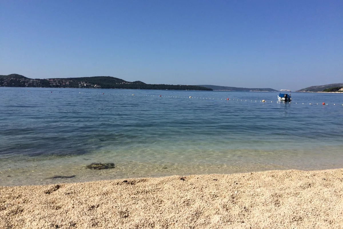 Clear turquoise water and a pebble shore at a beach near Trogir