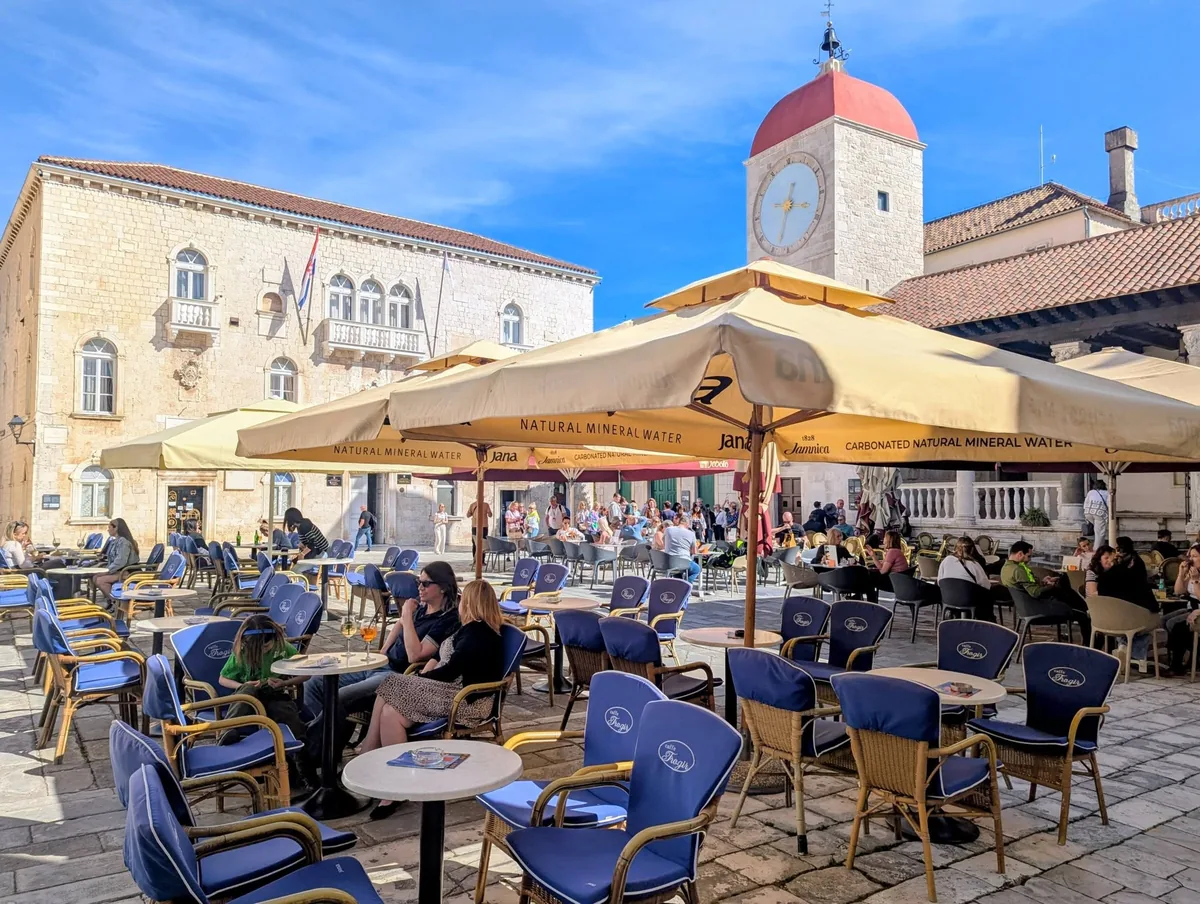 Café tables under umbrellas on Trogir's main square