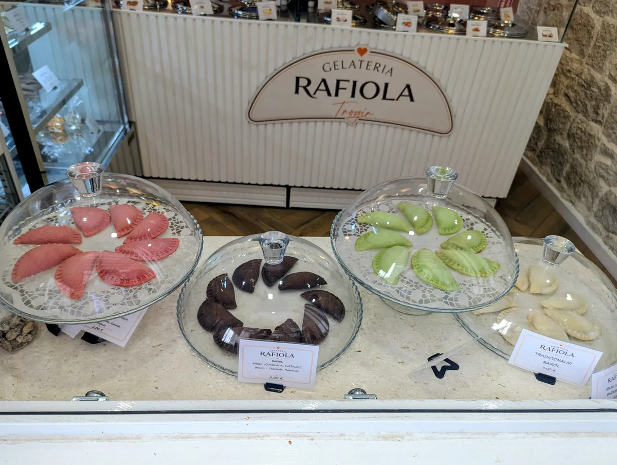 Trays of rafioli, Trogir's almond-filled pastries, in a glass display case at a gelateria in the old town