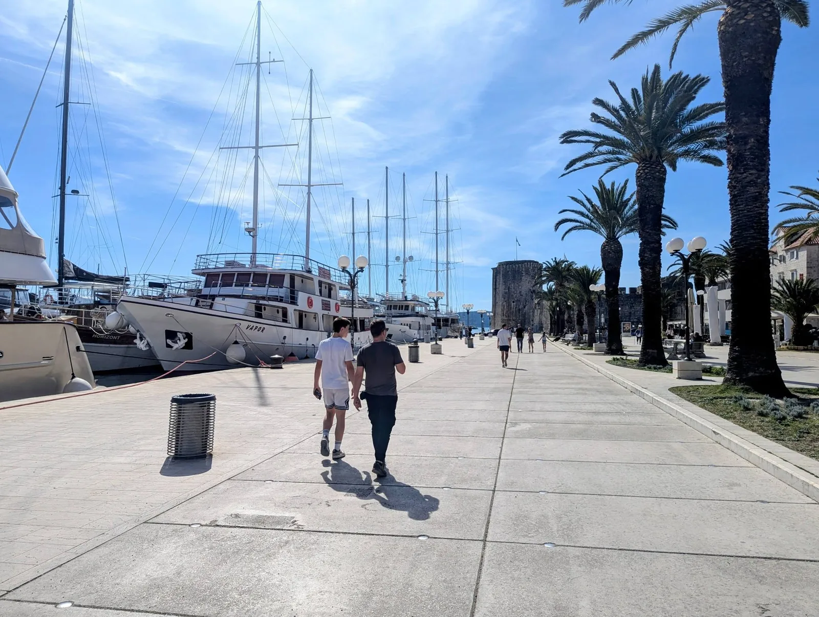 The palm-lined Riva promenade in Trogir with sailing boats moored along the waterfront